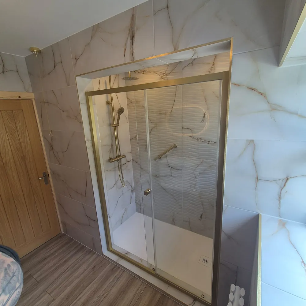 Finished walk-in shower with gold frame and marble tiling