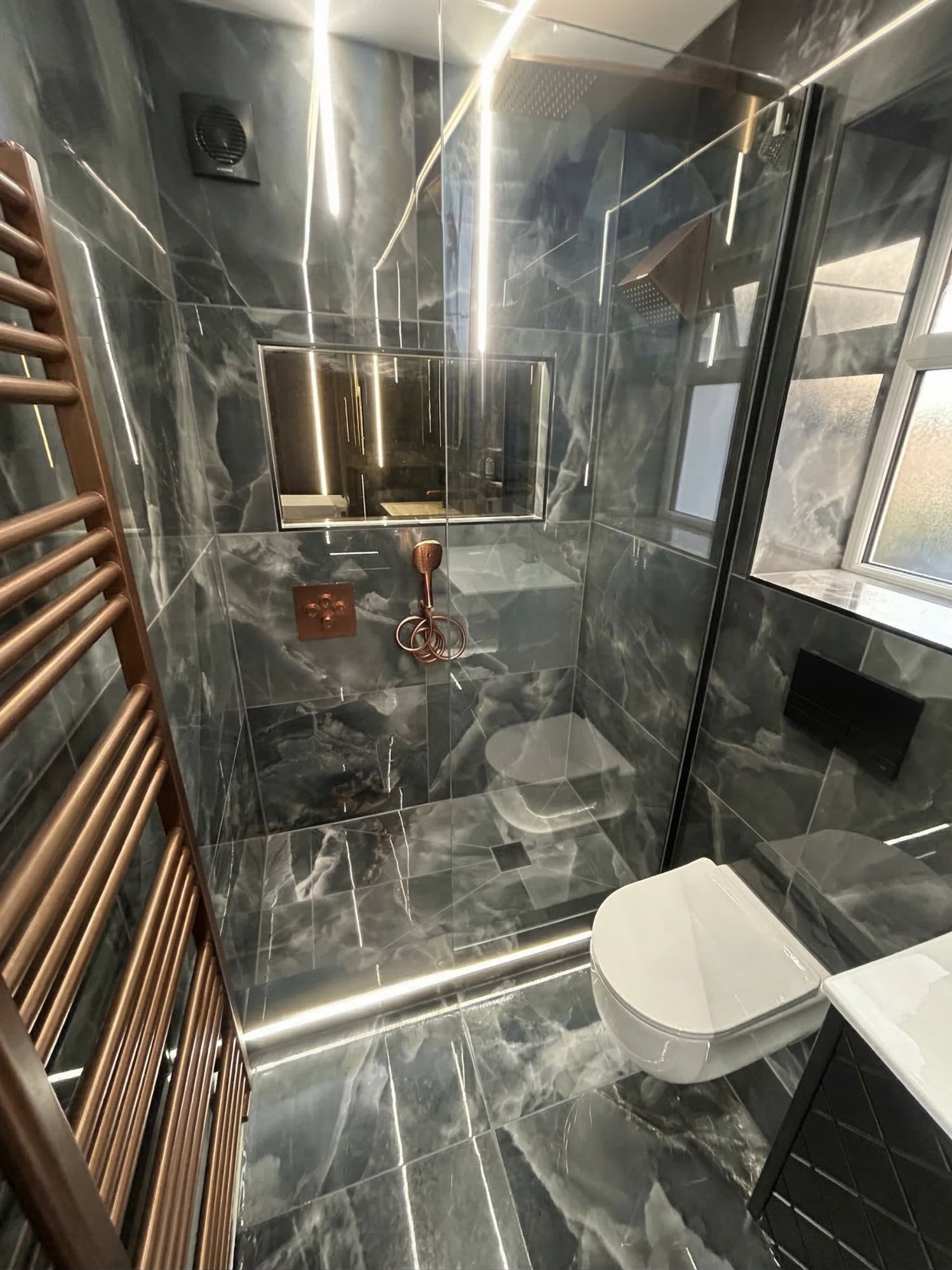 Dark marble bathroom with copper fittings