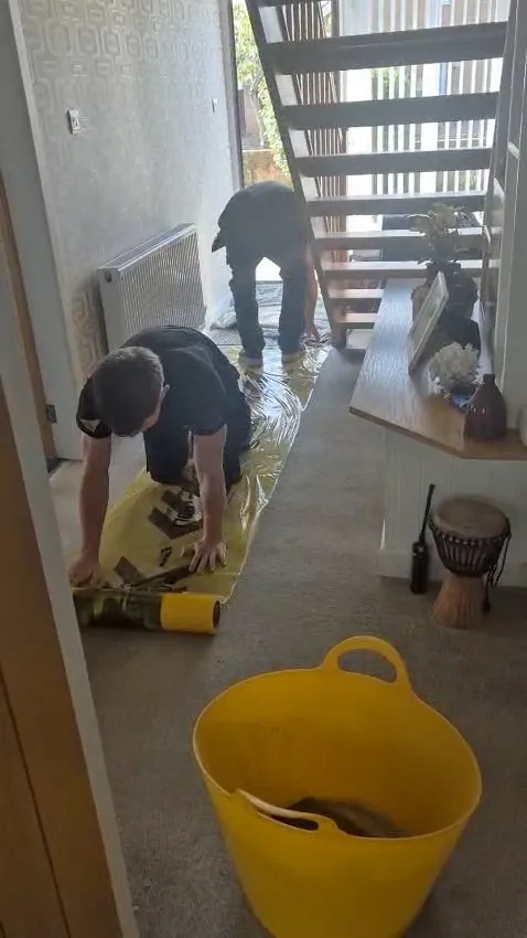 Two Danvers Northwest team members rolling out floor protection from the front door, through the hallway and stairs